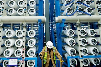 A worker checks the bank of pressure vessels that force seawater through the membranes